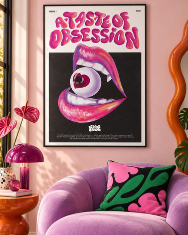 A Taste of Obsession poster framed on a pink wall above a lilac armchair