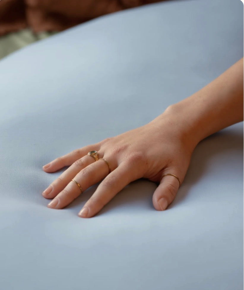 Close-up of the baby blue pillow fabric with a hand resting on it