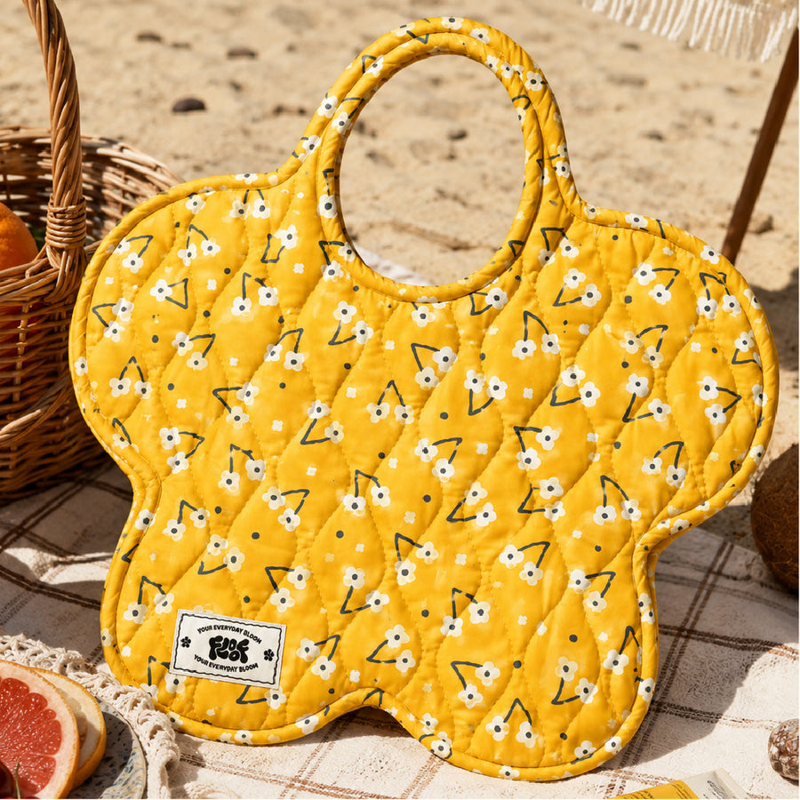 The butter yellow daisy print bag on a picnic blanket