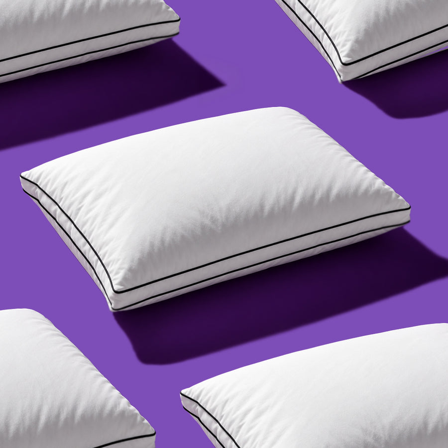 Several Floof Cloud Pillows arranged in rows, showing the navy piping along each edge